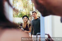 Smiling young couple at entrance door with wine bottle 5pz9wb