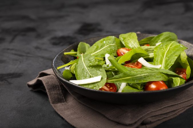 Arugula salad with tomatoes on dark background.