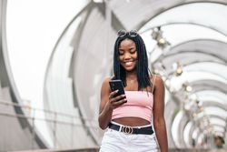 Portrait of a Black young woman enjoying the summer in the city using smartphone