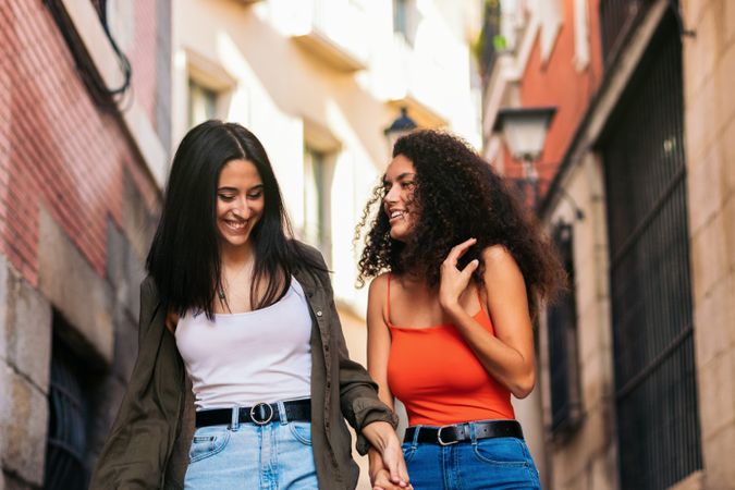 two young women walking down street stairs smiling holding her hands