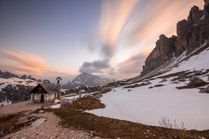 Tiny house in snowy valley with mountains