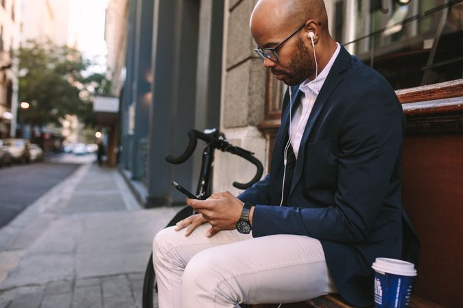 Businessman wearing headphones and listening to music from mobile phone