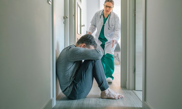 Female doctor running to help patient with mental disorder sitting on floor