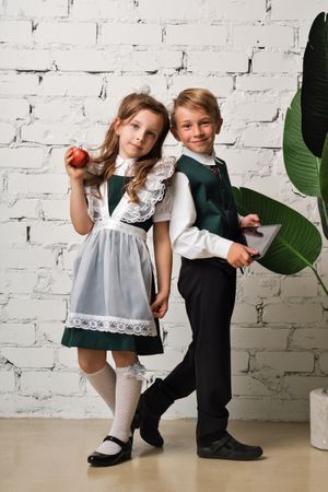 Portrait two elementary school students in uniform with apple and tablet pc