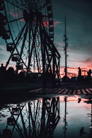 Silhouette of Ferris wheel beside body of water during sunset