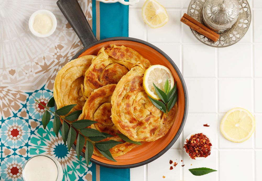 Top view of roti skillet served with citrus, tea and milk