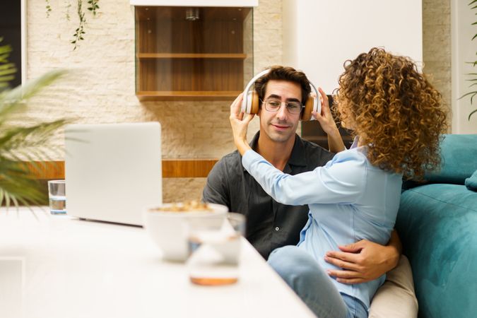 Loving couple playing with headphones while spending time together in living room