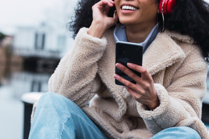 Cheerful Black woman listening to music at lakeside