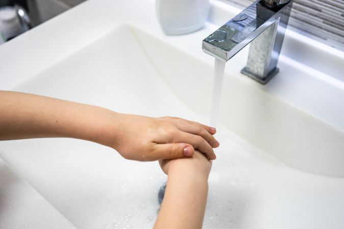 Person rinsing hands at sink