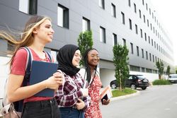 Three happy female students leaving campus together