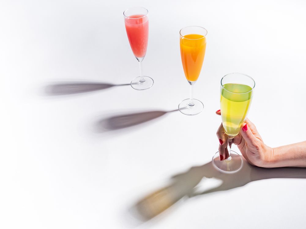 Hand and glasses of bright colorful drinks on table