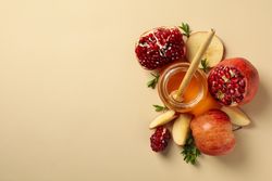 Looking down at open pomegranate, honey pot and sliced apple