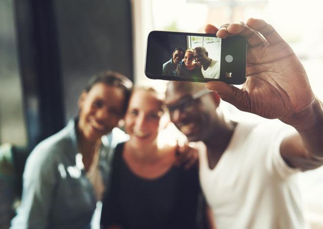 Three good friends pictured from a smart phone screen taking a selfie
