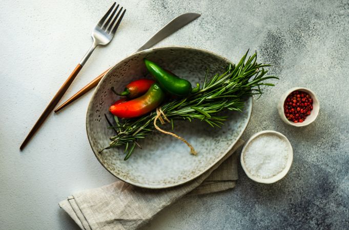 Grey bowl with rosemary bunch and spicy peppers