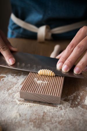 Crop woman making gnocchetti pasta