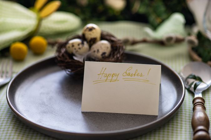 Easter table setting with card on plate with decorative nest