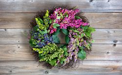 Colorful artificial wreath made of flowers and leaves on vintage wood background