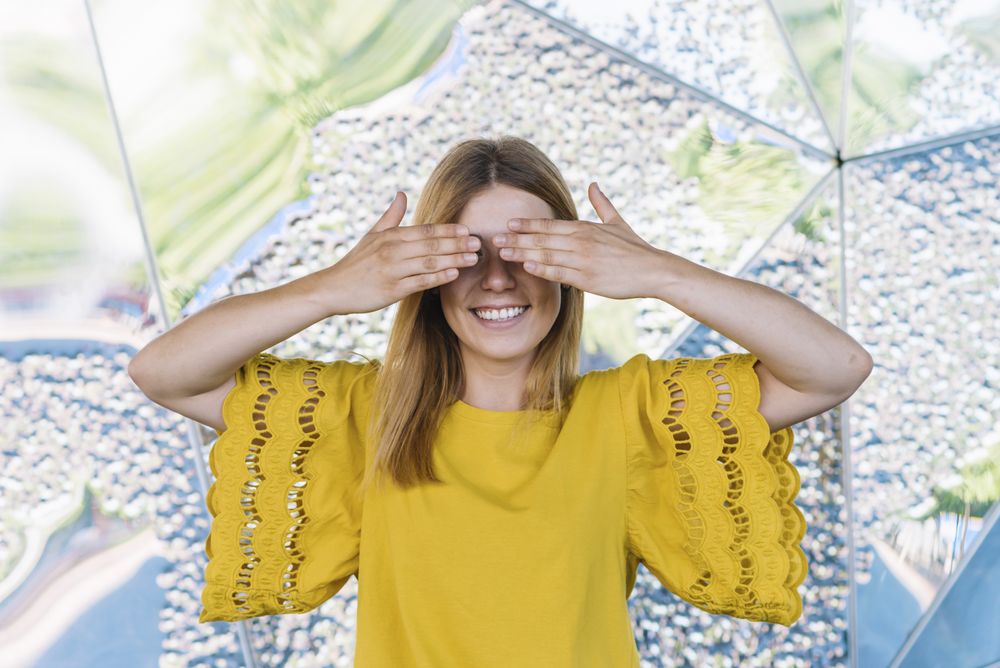 Young shy woman covering eyes