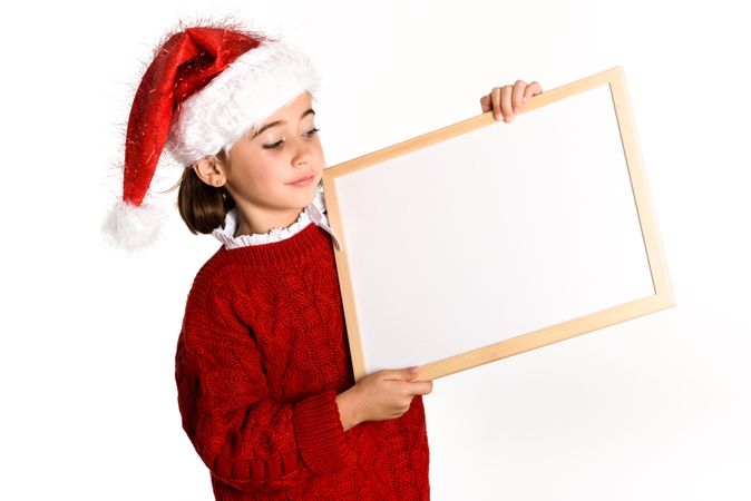 Girl in Santa outfit holding blank board