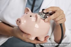 Doctor Holding Stethoscope to Piggy Bank 5oDkVx