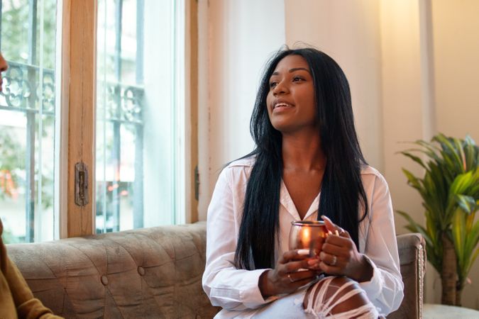 Black Latina woman having a drink in an indoor space