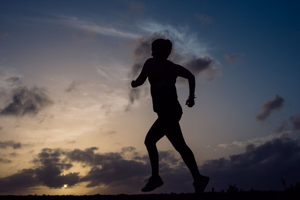 Jumping woman and sky with clouds at sunset