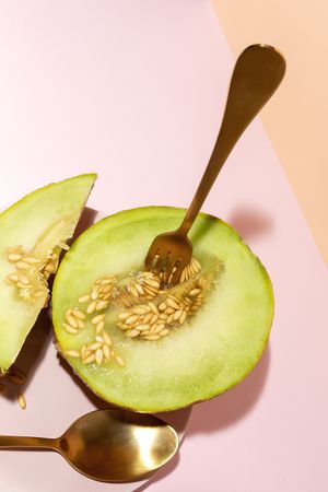 Sliced small melon on plate with spoon and fork