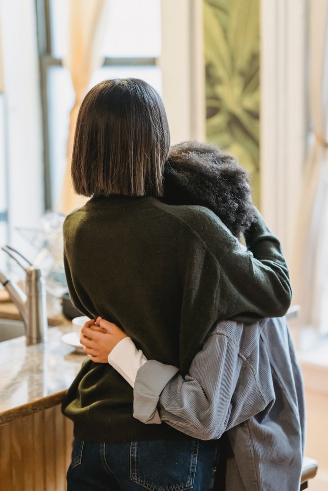 Back view of mother hugging a teenage kid