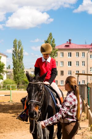 Young equestrian receives instruction during horseback riding session.