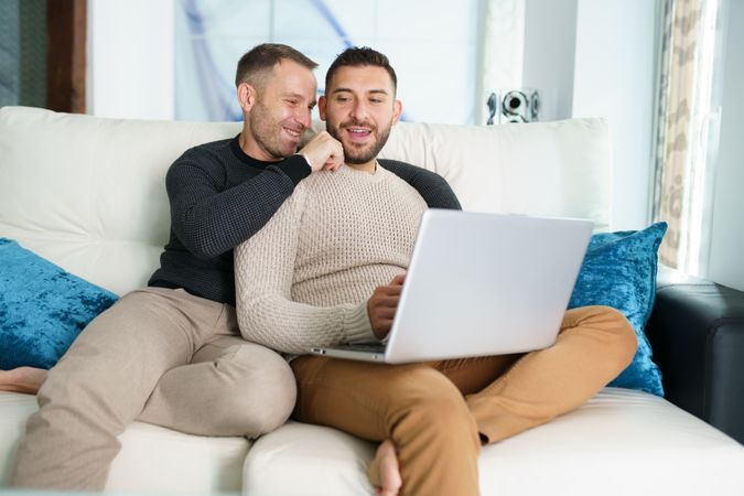 Two men chilling on couch with laptop