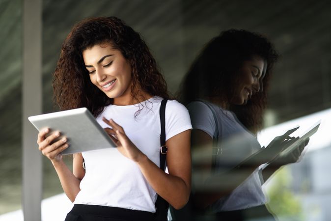 Smiling Arab woman using digital tablet in front of office building, copy space