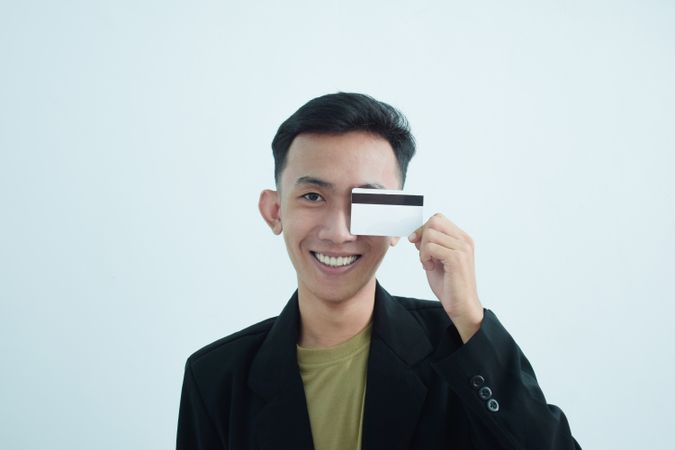 Happy Asian young businessman wearing suit with tshirt and holding blank credit card