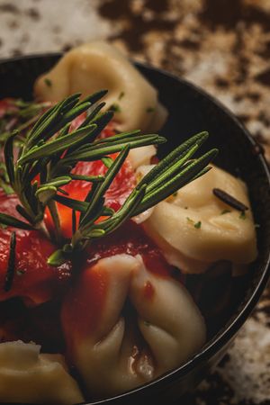 Plate of delicious ravioli with tomato sauce served on table
