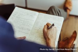 Close up of a man’s hand holding a pen and writing in a diary 5zRvP5
