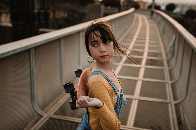 Girl with skateboard on walkway