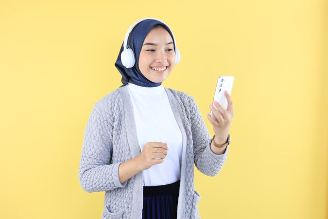 Young Muslim Woman Playing Music on Her Phone and Hearing with Headphone