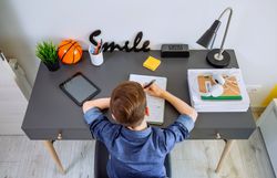 Top view of unrecognizable boy doing homework in his bedroom