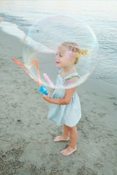 Happy little girl playing with toy at beach
