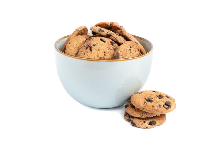 Bowl with tasty chocolate chip cookies on plain background