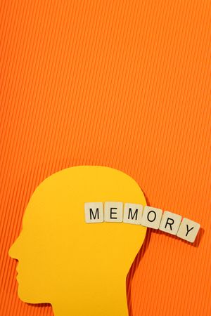 Orange duotone flat lay of head with the word “memory” in wooden blocks, vertical