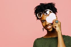 Portrait of a smiling young man holding a pink heart, isolated on pink studio background