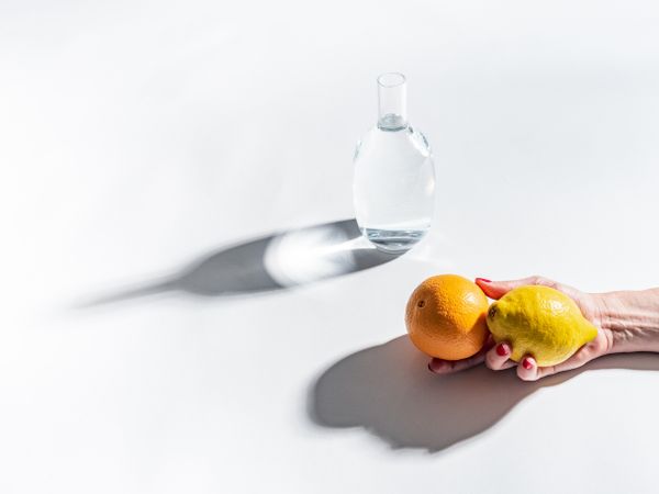 Composition of a hand with citrus and jar of water