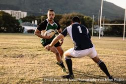 Rugby players running with ball and tackling during game 48O3X5