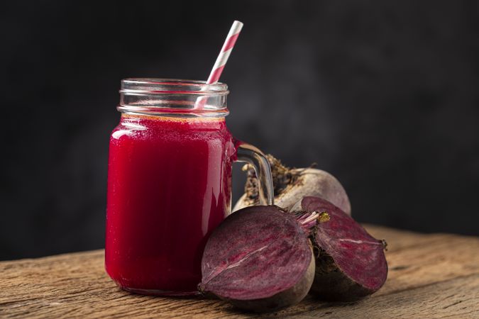 Red beet juice in a glass cup on the wooden table.