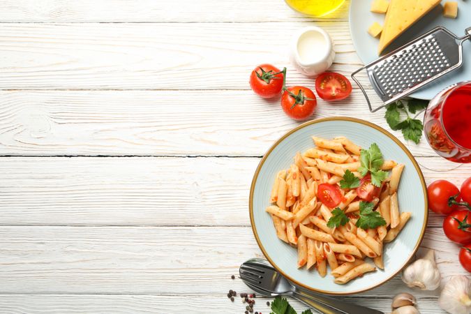 Composition with plate of tasty pasta and ingredients for cooking on wooden background