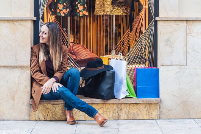 Content young woman in casual outfit resting on street after shopping