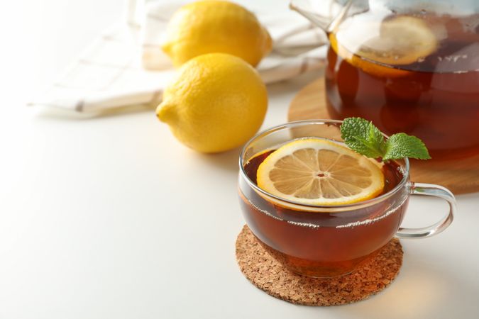 Cup of tea, mint, lemon, tea pot and towel on blank background, copy space