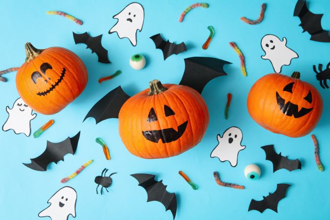 Halloween concept with pumpkins, ghosts, candies and bats on blue background