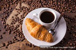 Coffee and croissant surrounded by coffee beans 5RVVoN