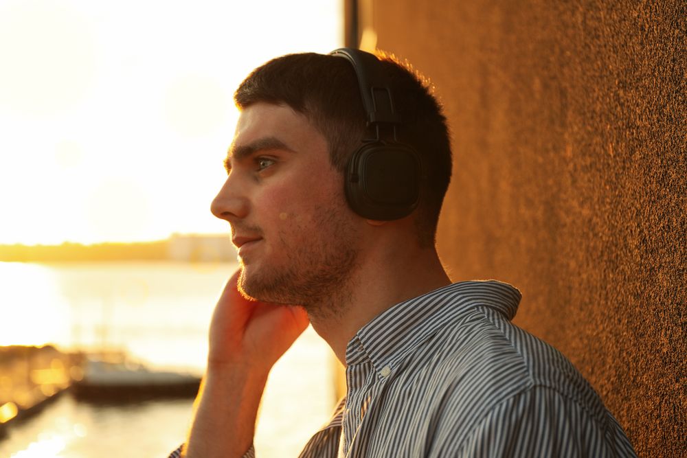 Young man in headphones listen music. Amazing sunset